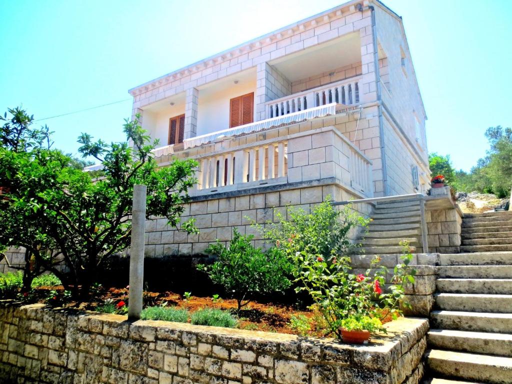 a house with a stone wall and stairs at Apartments Toncic in Lumbarda