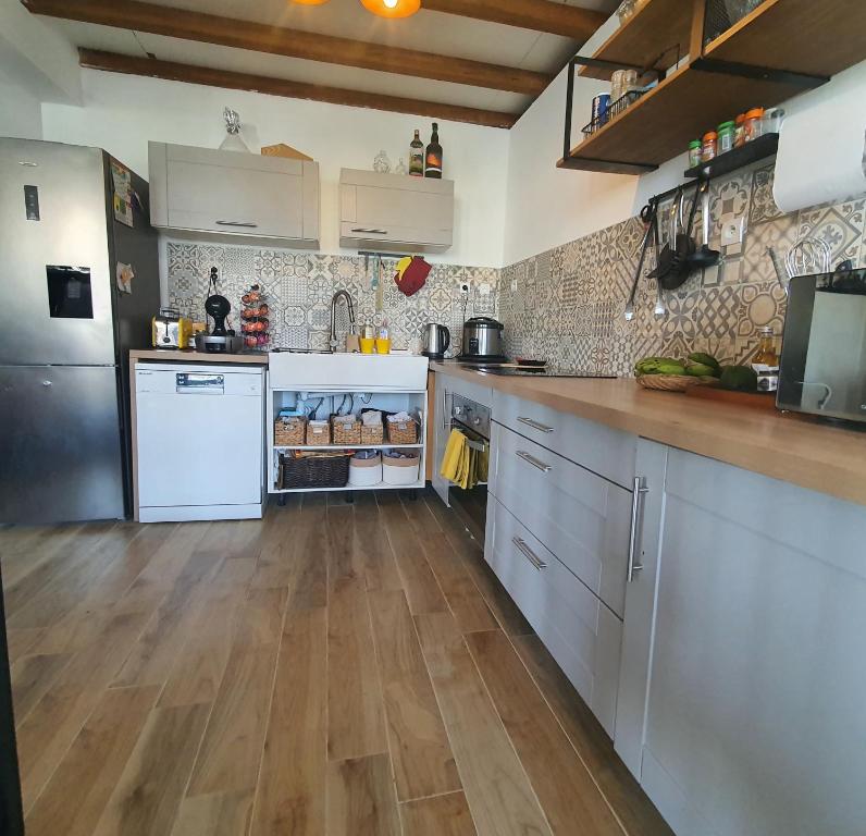 a large kitchen with white appliances and wooden floors at Appart Angel in Saint-Benoît