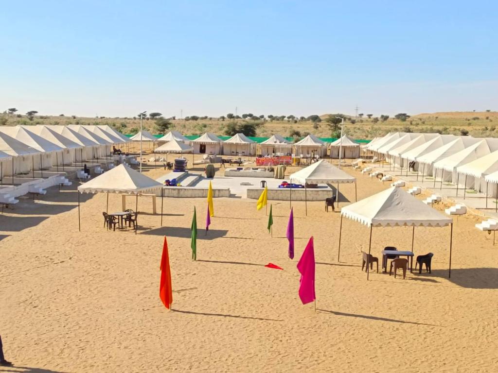 Aroma Desert Safari Camp في Sām: شاطئ فيه مظلات بيضاء وطاولات وكراسي