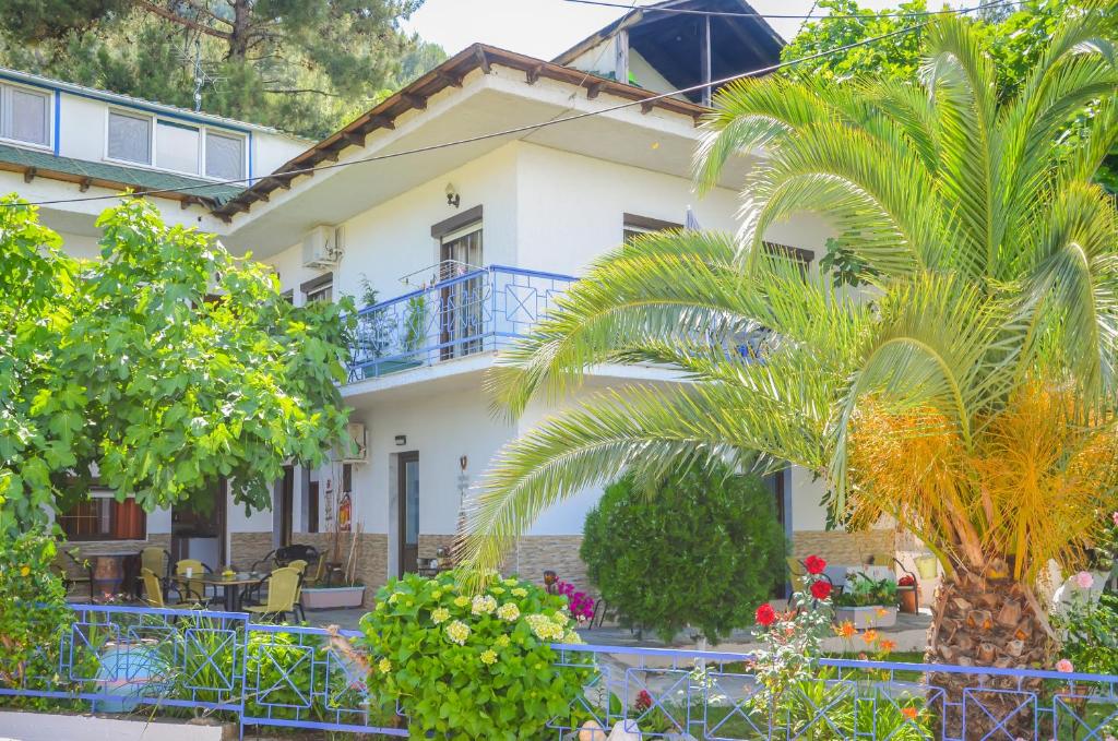 a white house with a palm tree in front of it at Studios Ifigenia in Skala Potamias