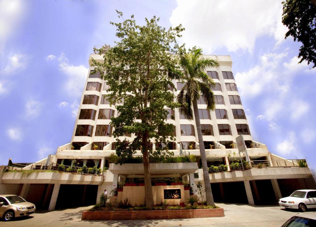 un edificio blanco alto con un árbol delante de él en The Oasis, en Vadodara