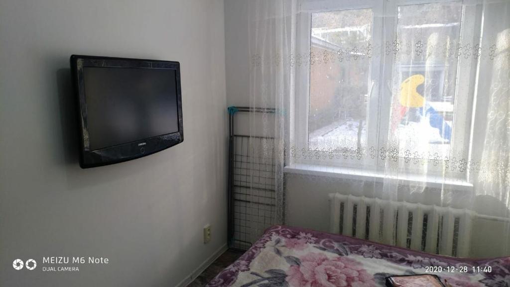 einen TV, der an einer Wand neben einem Fenster hängt in der Unterkunft 1 комнатные апартаменты возле ст. метро Москва in Almaty