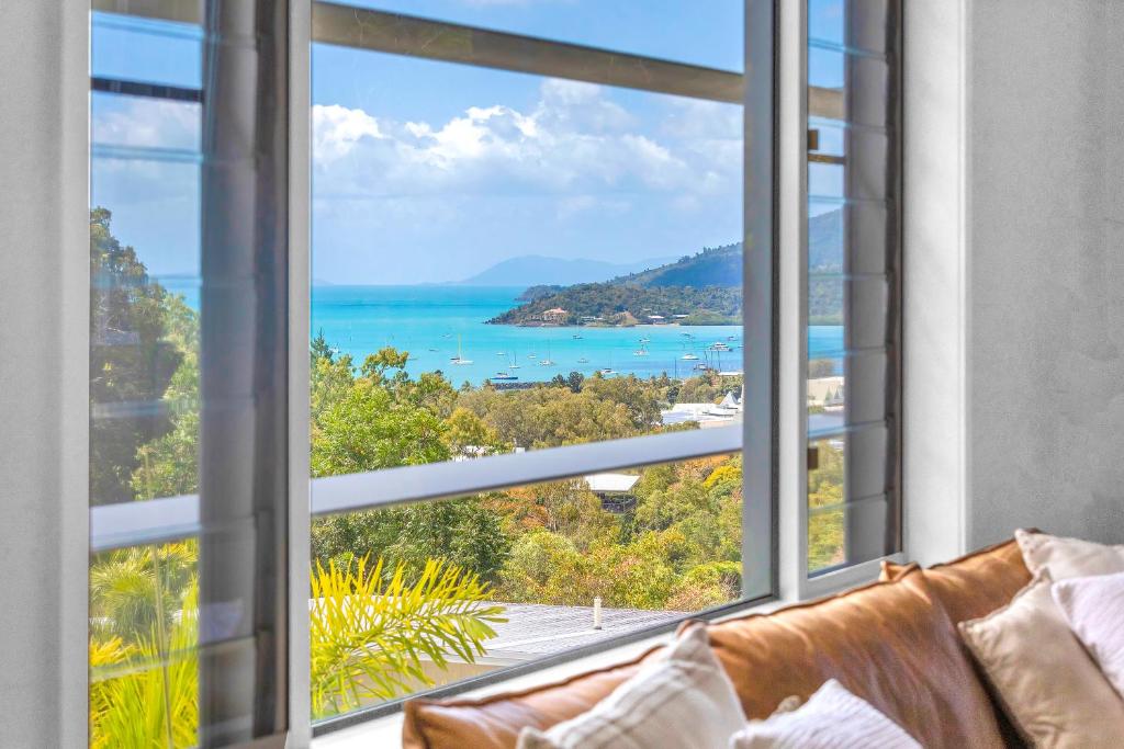 a living room with a large window looking out at the ocean at 30 Airlie Beach Bliss at The Summit in Airlie Beach