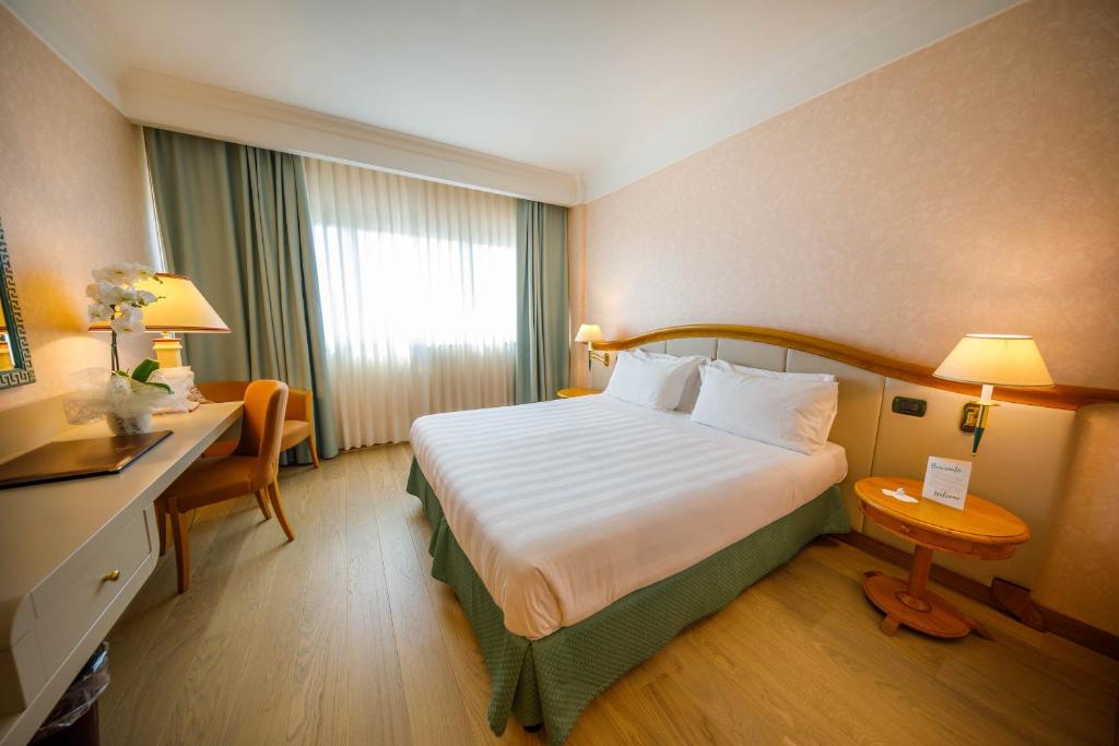 a hotel room with a large bed and a desk at Perugia Plaza Hotel in Perugia