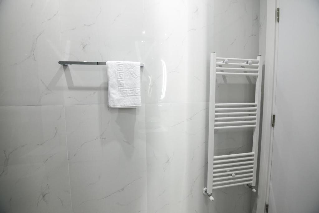 a white bathroom with a towel hanging on a wall at N Hotel BY NOSHI in Rinas