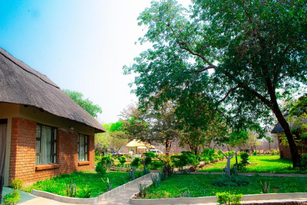 a brick building with a tree next to a yard at iroCK Lodge in Victoria Falls