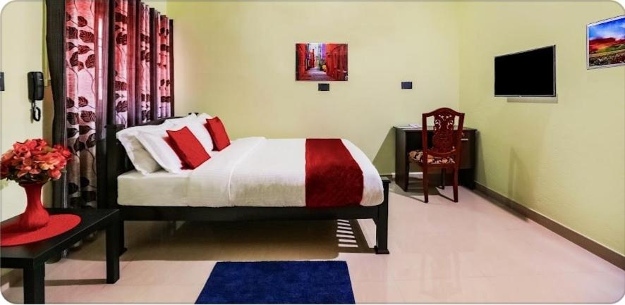a bedroom with a bed and a table and a tv at Urban Rose Homestay in Kannur