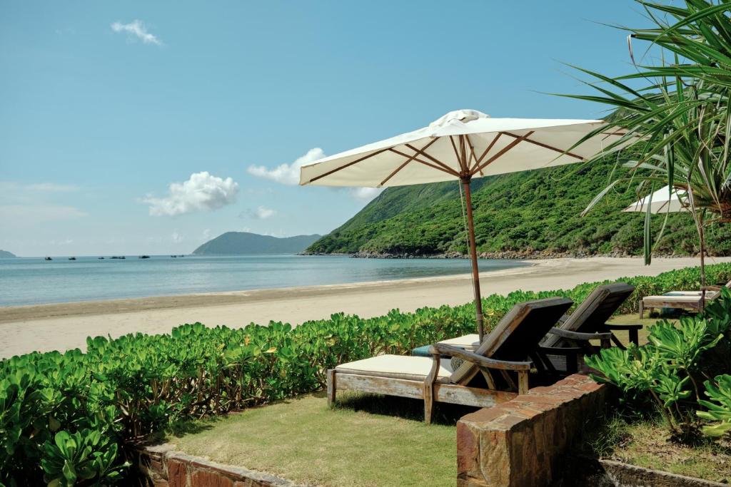 a beach with two lounge chairs and an umbrella at Poulo Condor Boutique Resort & Spa in Con Dao