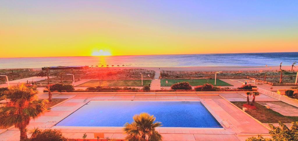 - une vue sur la piscine et l'océan au coucher du soleil dans l'établissement Beautiful Vacation Rental in Le Barcars, France, au Barcarès