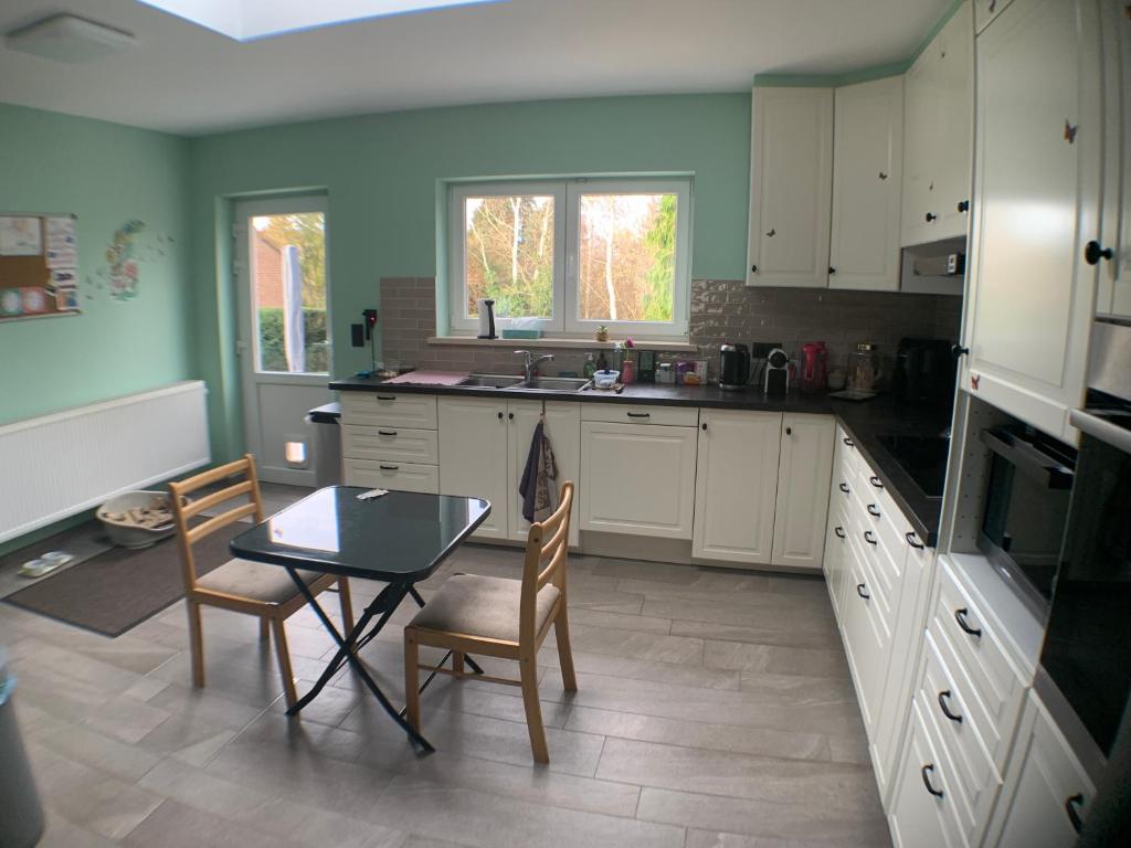 una cucina con mobili bianchi, tavolo e sedie di Chambre dans habitat partagé chez Séverine a Nivelles