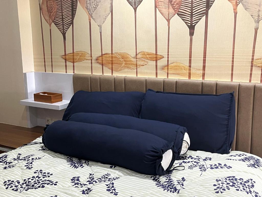 a bed with blue pillows on top of it at Cozy 2 BR Sudirman Suites Apartment in Bandung