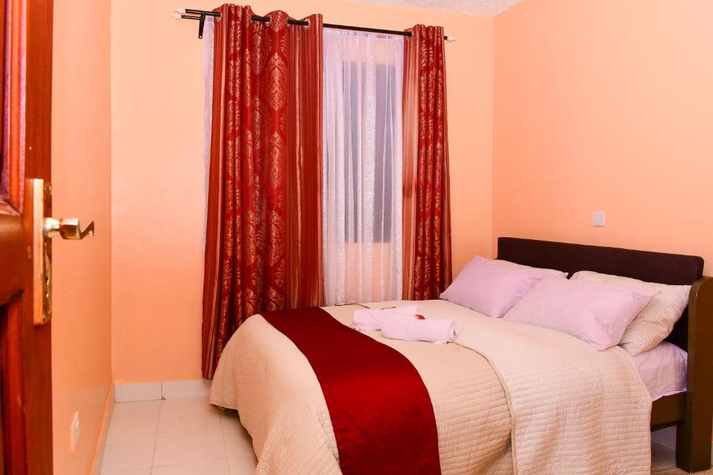 a bedroom with a bed with red drapes at The Lotus Stay-in at Paradise Apartments, Embu in Embu