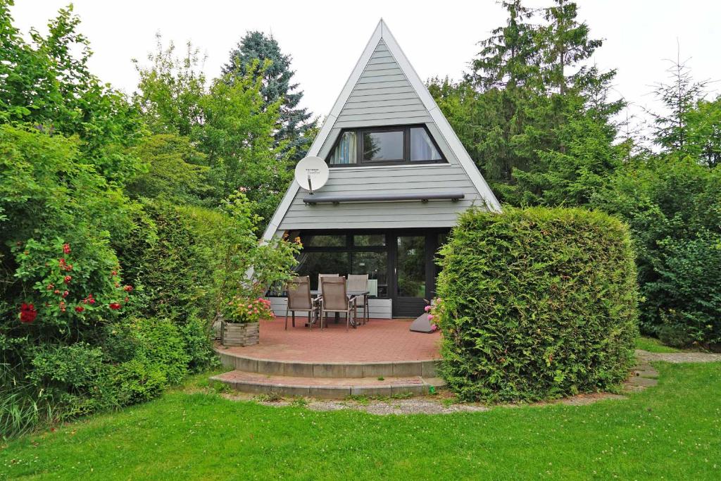 a house with a triangular roof with a patio at Zeltdachhaus _ grosses Grundstueck in Damp