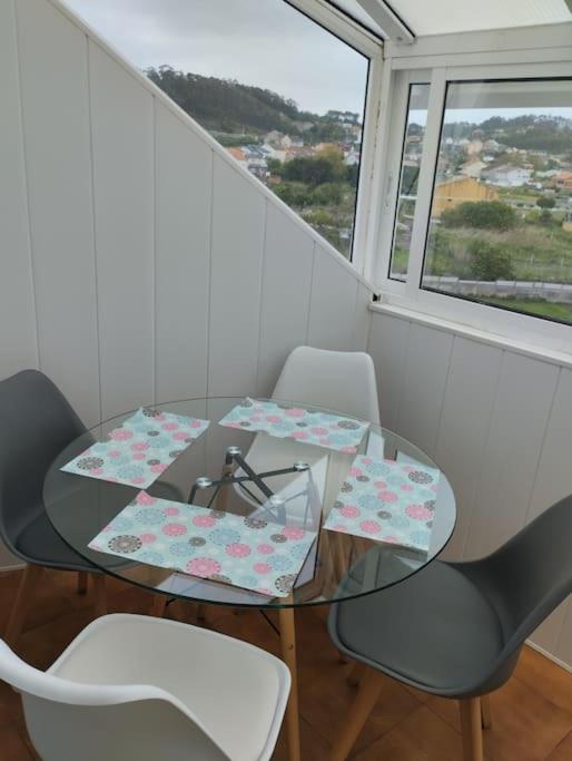 a glass table with two chairs and a window at Piso en Grove in O Grove