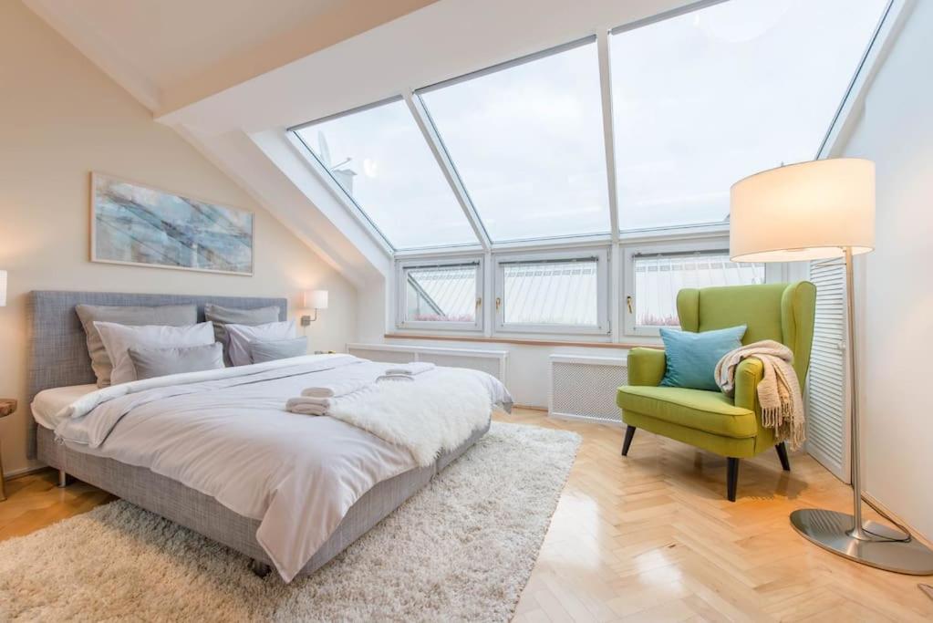 1 dormitorio con 1 cama grande y 1 silla verde en Venus Apartments - Skylit - Deluxe Loft with Skylight, en Budapest
