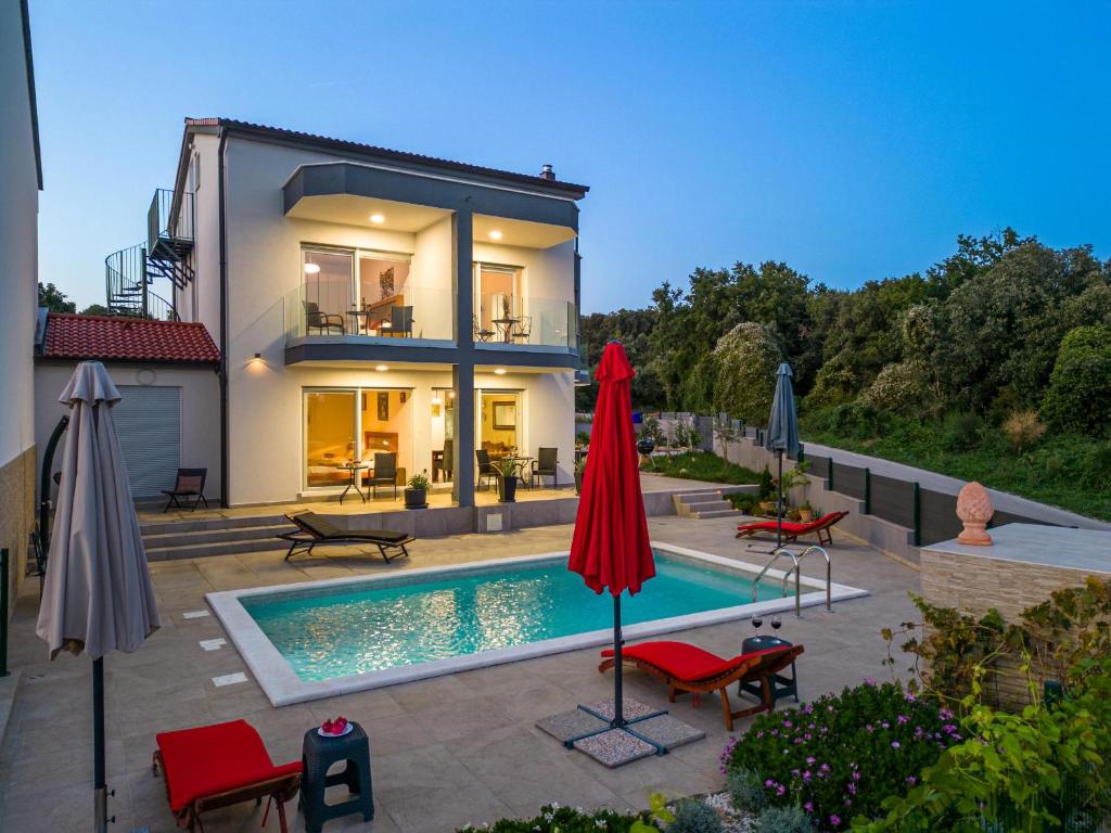 a house with a swimming pool and two umbrellas at Villa Rozeta in Marčana