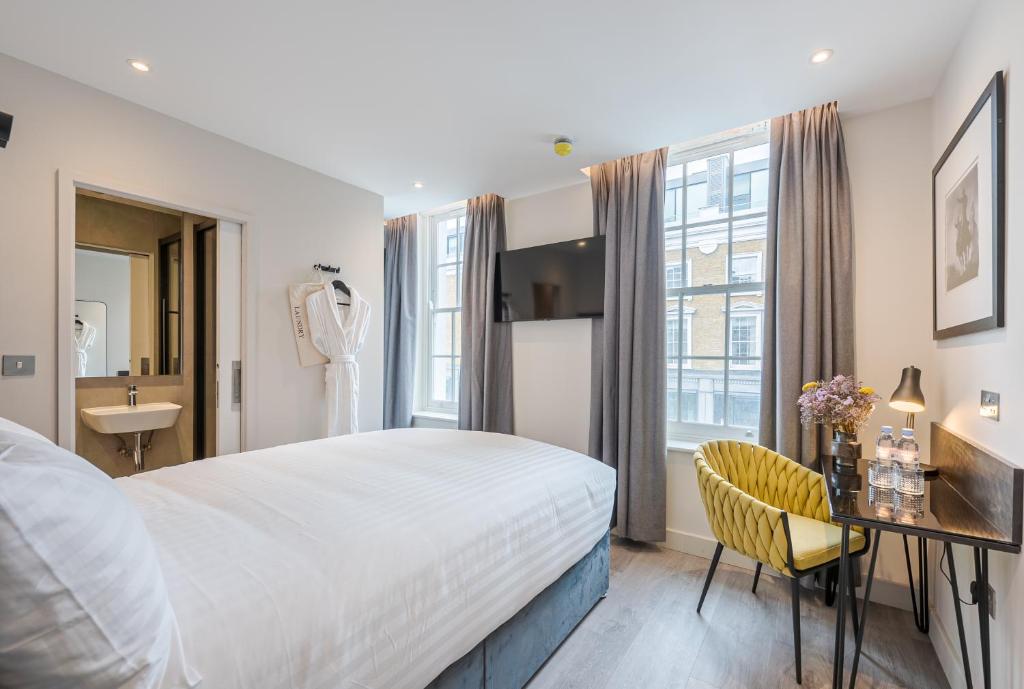 una camera d'albergo con letto, scrivania e lavandino di St Pancras Inn a Londra