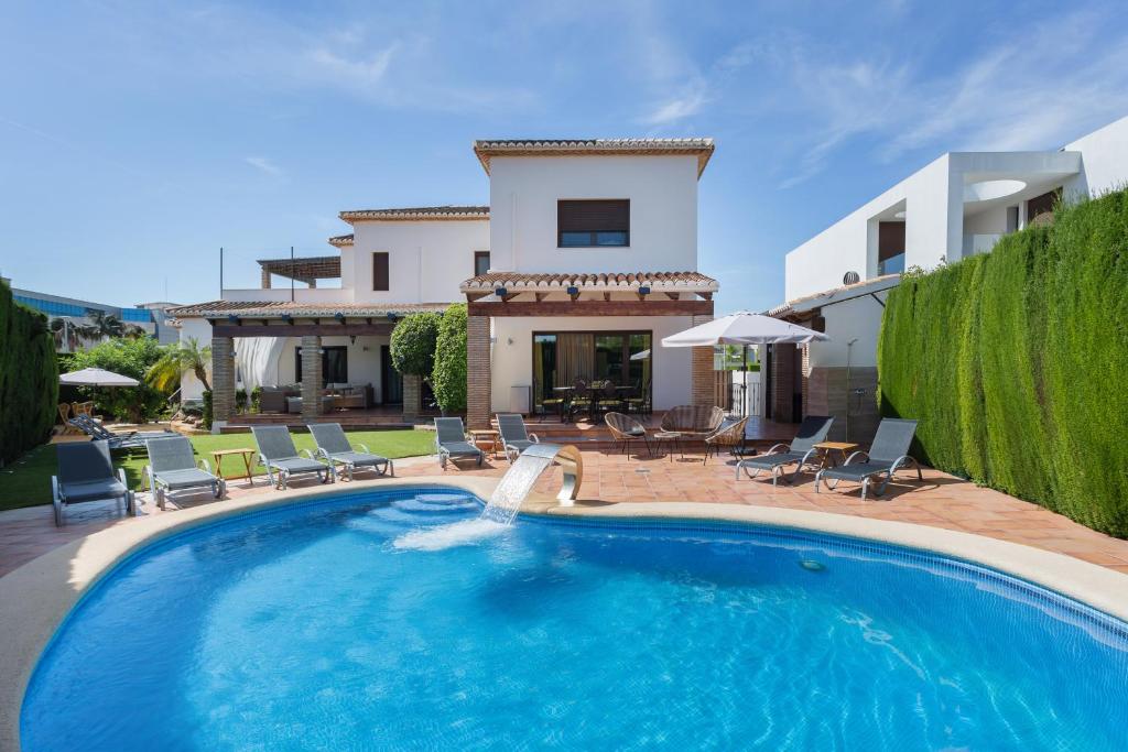 a swimming pool in front of a house at Resort Villa Luny Gandia in Gandía