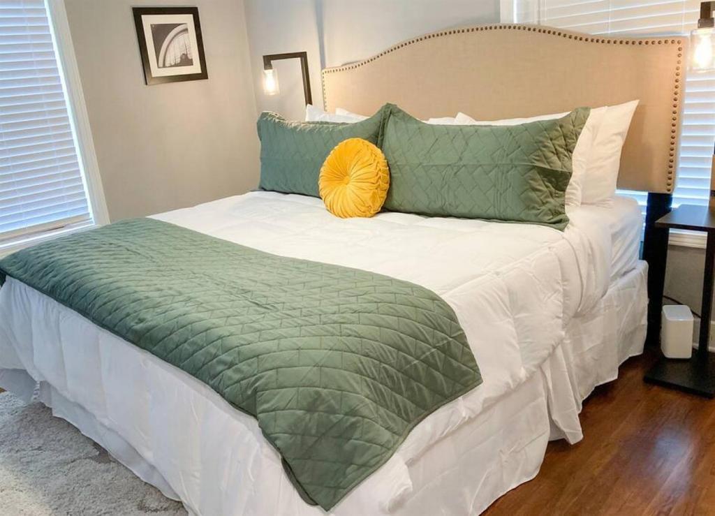 - un lit avec des draps et des oreillers verts et blancs dans l'établissement Oak Forest Cottage, à Little Rock