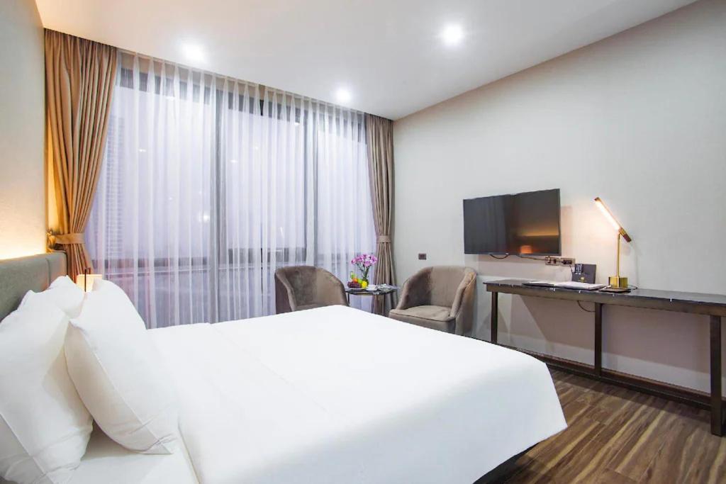 a hotel room with a large white bed and a desk at Western Skyline Hotel - Số 2 Đại Lộ Thăng Long - by Bay Luxury in Hanoi