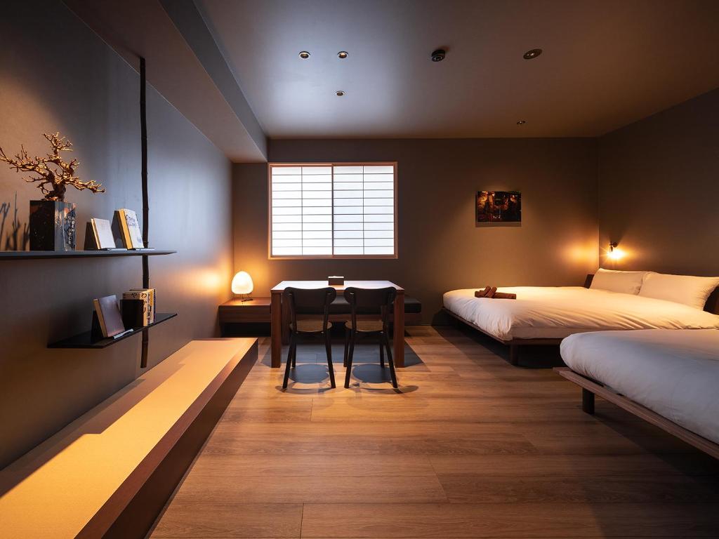 1 Schlafzimmer mit 2 Betten, einem Tisch und einem Fenster in der Unterkunft YANAKA SOW in Tokio