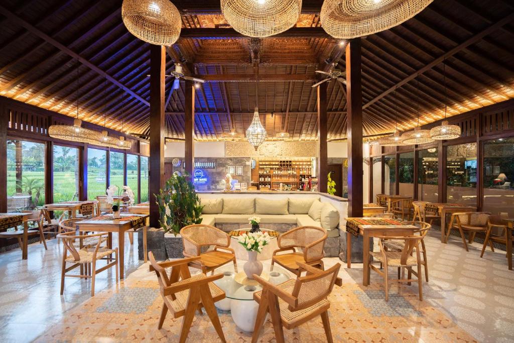 ウブドにあるBarong Bali Resort Ubudのテーブルと椅子、ソファ付きのレストラン