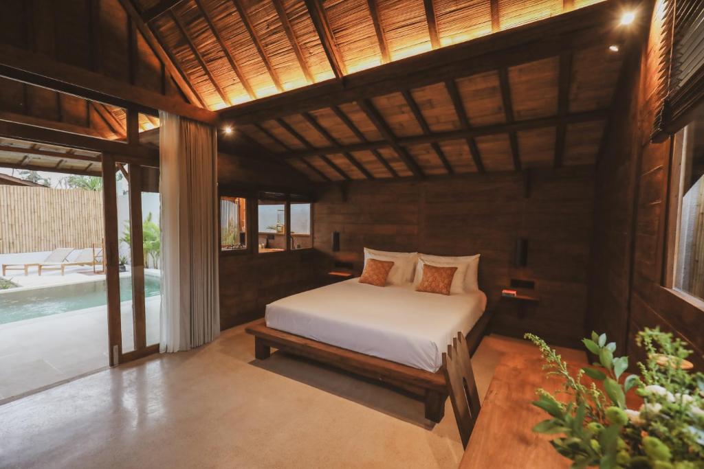 ein Schlafzimmer mit einem Bett in einem Zimmer mit einem Pool in der Unterkunft Kalyana Villa Gili Air in Gili Air