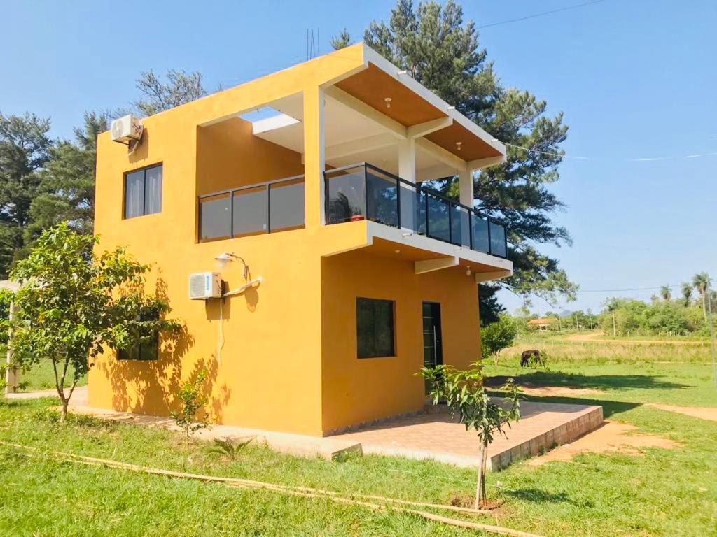 une maison jaune au milieu d'un champ dans l'établissement Casa Birnbaum Ruiz Diaz, à Carapeguá