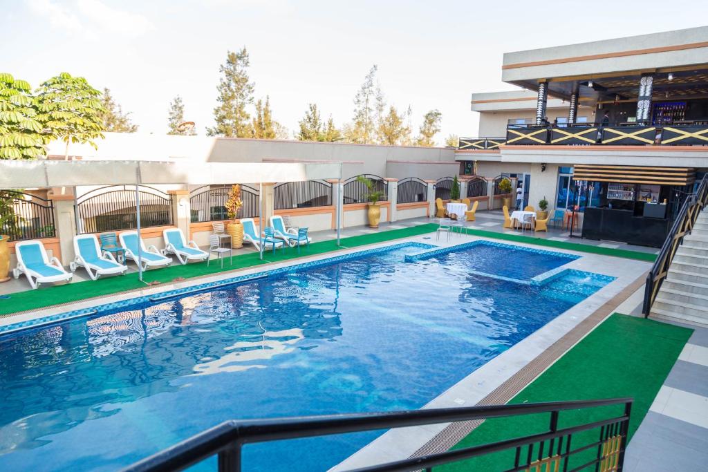 a swimming pool with chairs and a house at Olympic Hotel in Kigali