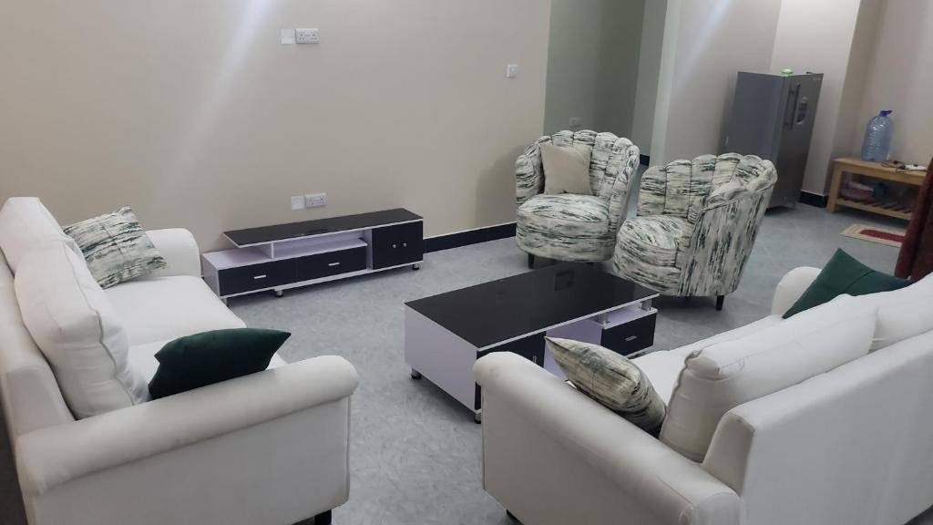 una sala de estar con sofás y sillas blancos en Calan Resdence, en Dodoma