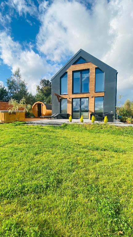 ein Haus mit einem großen Garten mit einem grünen Feld in der Unterkunft Domek na Kaszubach in Kamienica Szlachecka