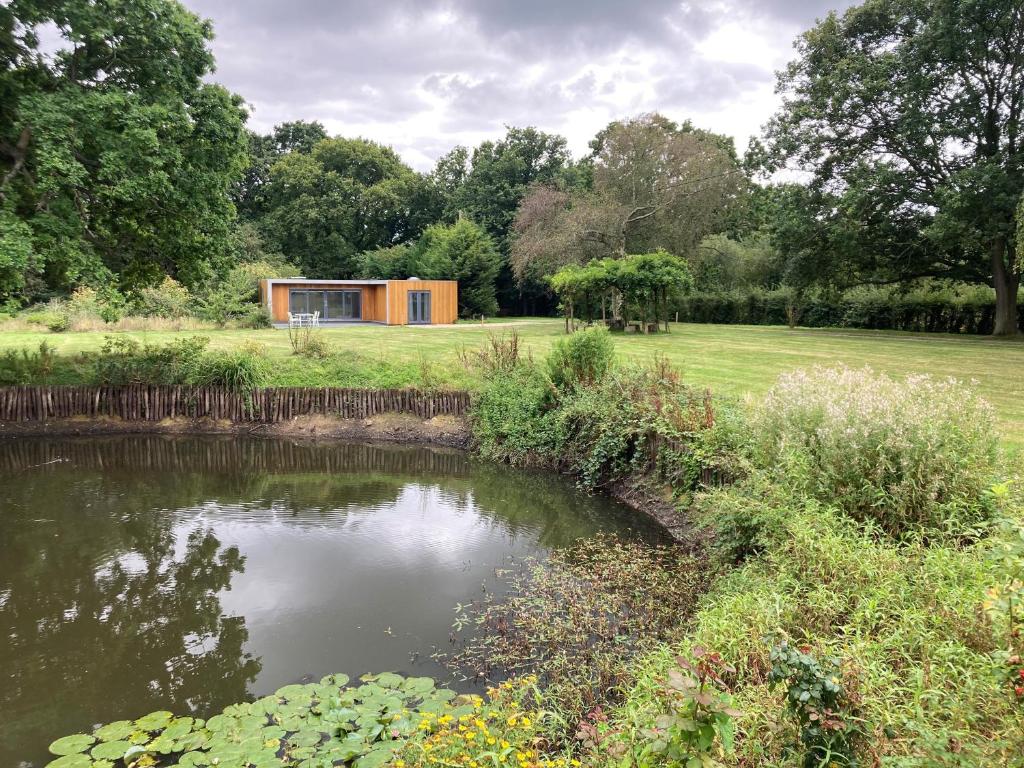 ein Haus inmitten eines Feldes mit einem Teich in der Unterkunft Rural Detached House Close To Canterbury in Canterbury