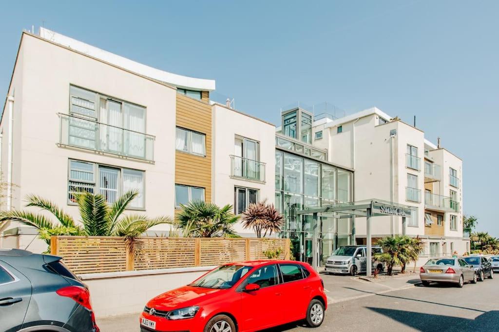 a red car parked in a parking lot in front of buildings at Lovely One Bedroom Flat in Bournemouth