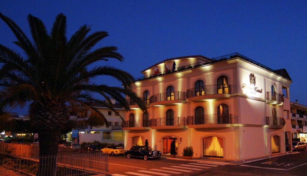 un grand bâtiment blanc avec un palmier en face dans l'établissement Bram Hotel, à SantʼEufemia Lamezia