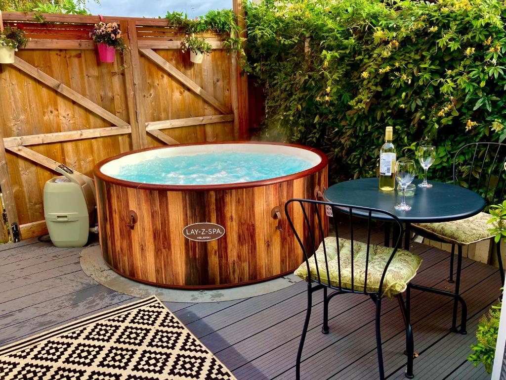 a hot tub on a deck with a table and a bottle of wine at Elkstone Studio Private Hottub Pet Friendly in Malvern Link