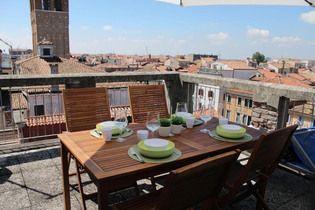 un tavolo in legno su un balcone con vista sulla città di Apartment with terrace in Chioggia's main square a Chioggia