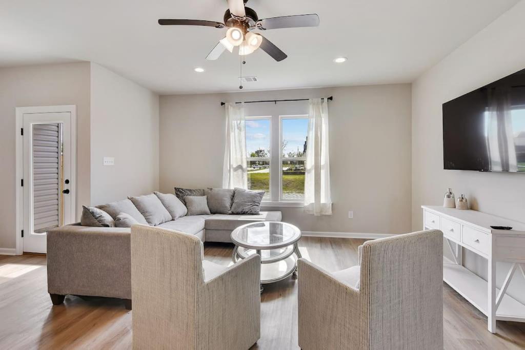 a living room with a couch and a ceiling fan at Brand-new home close to LSU campus in Baton Rouge