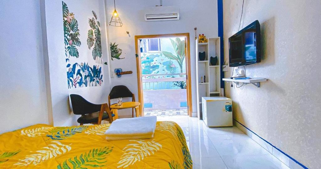 a bedroom with a bed with a yellow blanket and a window at Ngõ Saigon Homestay in Ho Chi Minh City