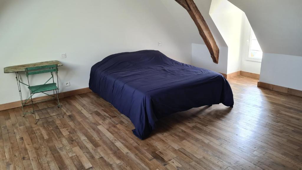um quarto com uma cama e uma mesa num piso de madeira em Maison Bourgueil em Bourgueil