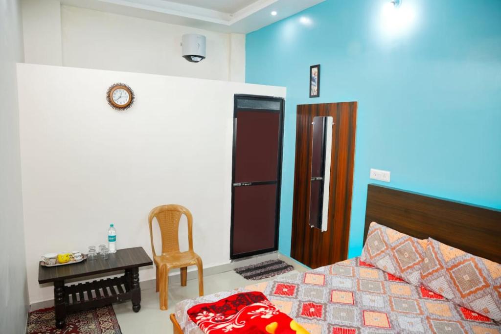 a bedroom with a bed and a table and a chair at Shree Home Stay in Ujjain