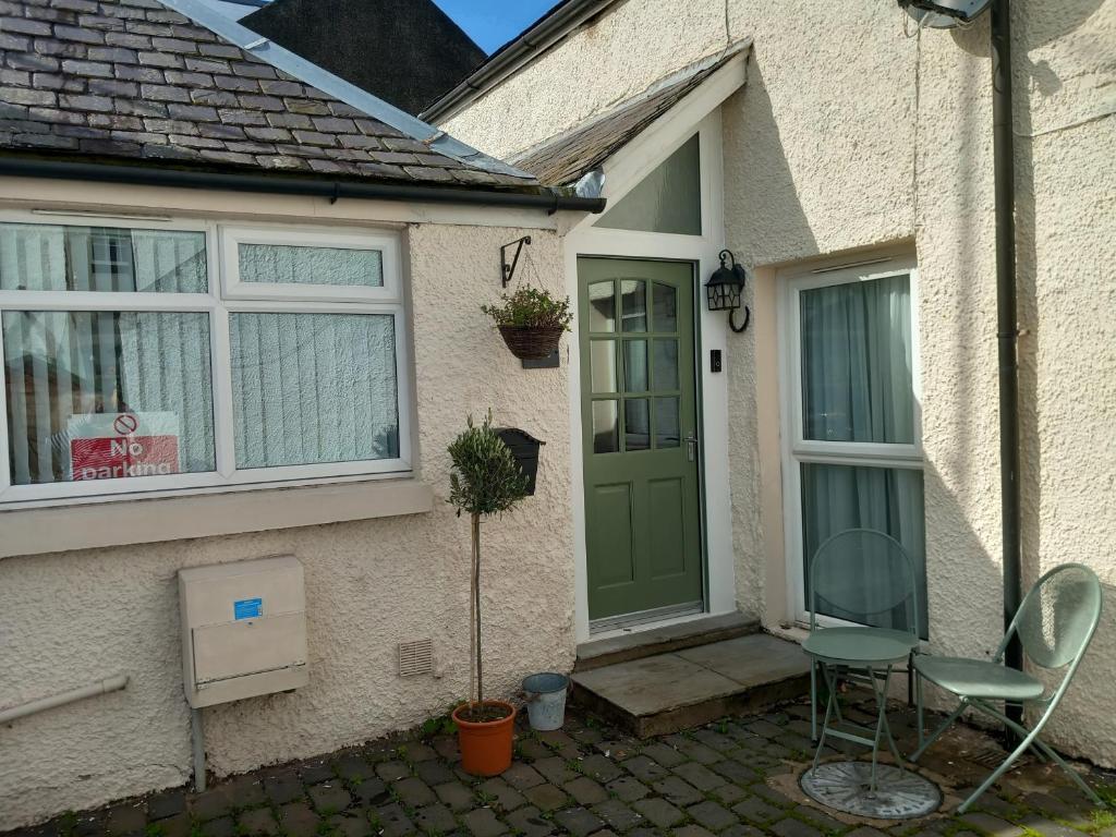 a house with a green door and a table and chair at Horseshoe Cottage in Coldstream