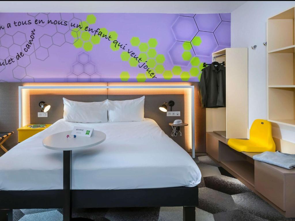 a bedroom with a bed with a table and a purple wall at ibis Styles Strasbourg Stade de la Meinau in Strasbourg