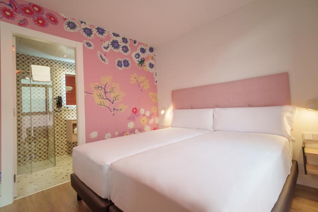 una camera da letto con un grande letto bianco con fiori sul muro di Spirit Apartamentos Valladolid Centro a Valladolid