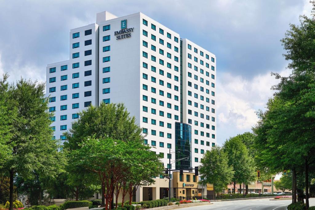 un grand bâtiment blanc avec des arbres en face d'une rue dans l'établissement Embassy Suites by Hilton Atlanta Buckhead, à Atlanta