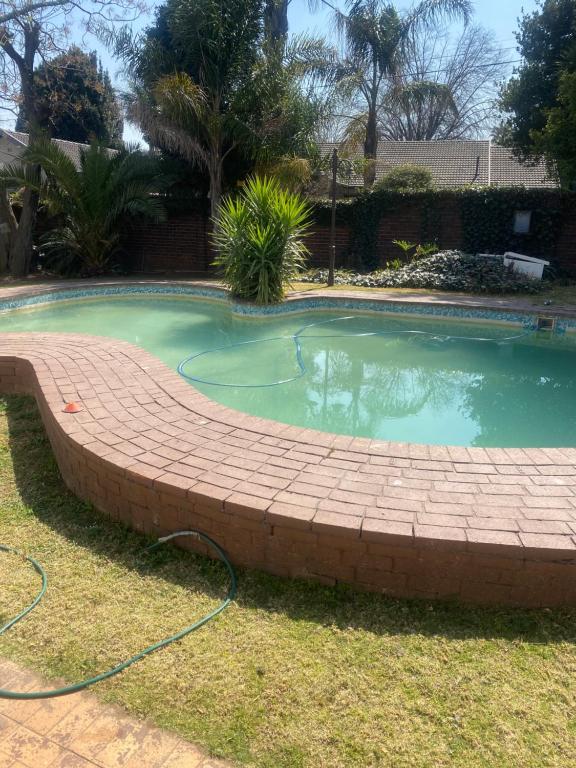 a swimming pool with a brick retaining wall around it at Eden homestay in Edenvale
