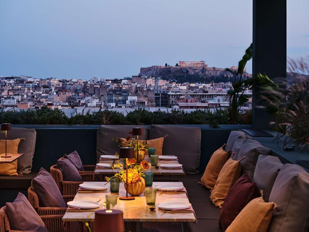 um restaurante com mesas e cadeiras com vista para a cidade em Radisson Blu Park Hotel Athens em Atenas