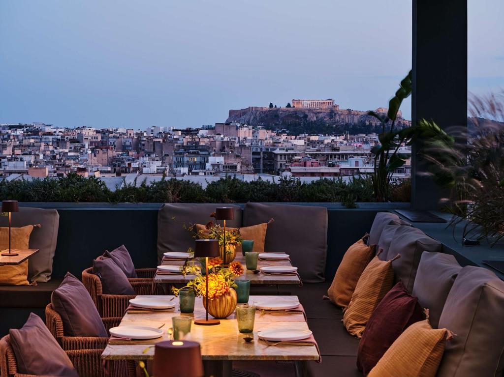 un restaurante con mesas y sillas y vistas a la ciudad en Radisson Blu Park Hotel Athens, en Atenas