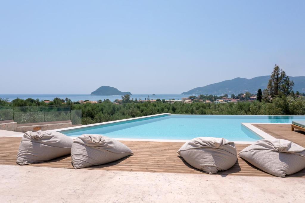 einen Pool mit zwei Kissen auf einer Holzterrasse in der Unterkunft Evylio Stone Houses in Lithakia