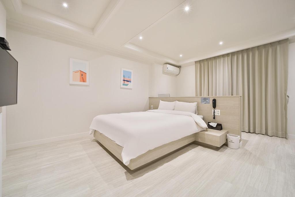 a white bedroom with a bed and a television at Hotel Yeogiuhtte Gumi Indong 2 in Gumi