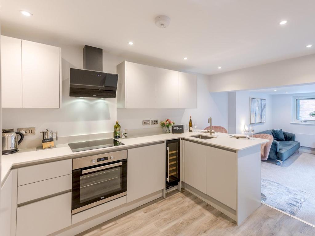 a kitchen with white cabinets and a living room at Pass the Keys Bouvardia Modern town centre apartment in Shrewsbury